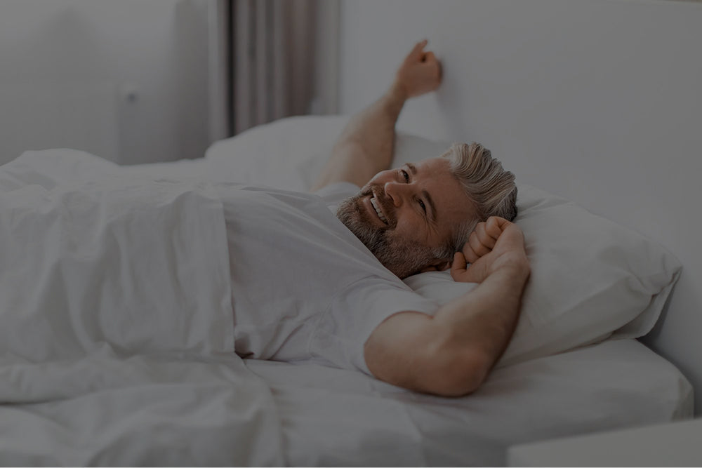 Entspannter Mann streckt sich morgens schmerzfrei auf einer ergonomischen Wolkenreich Luftkernmatratze